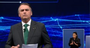 Jair Bolsonaro de terno e gravata falando no estúdio do debate da band