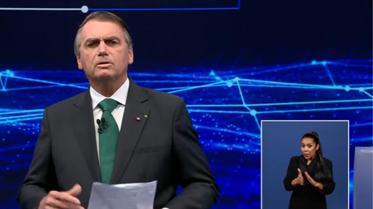 Jair Bolsonaro de terno e gravata falando no estúdio do debate da band