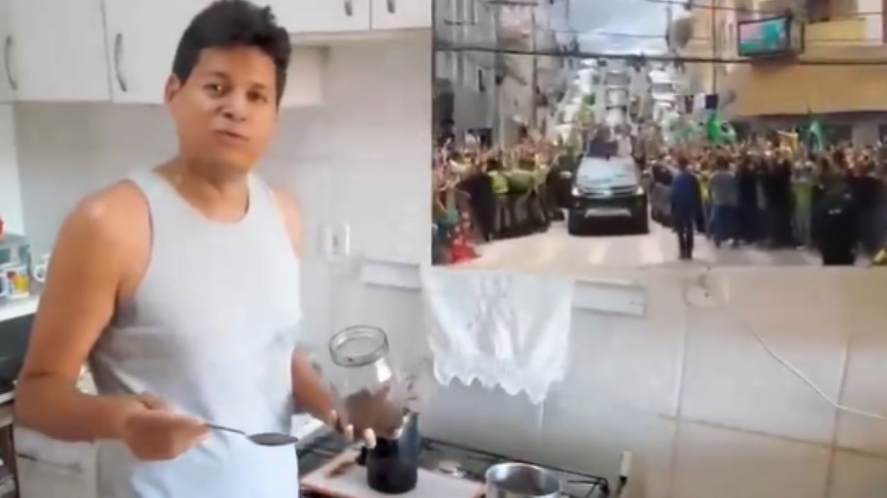 Daniel Sucupira de camiseta cinza na cozinha de casa, falando para a câmera, com vídeo de Bolsonaro ao lado