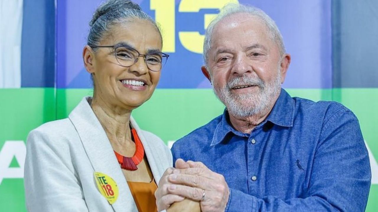 Marina Silva e Lula sorrindo e de mãos dadas