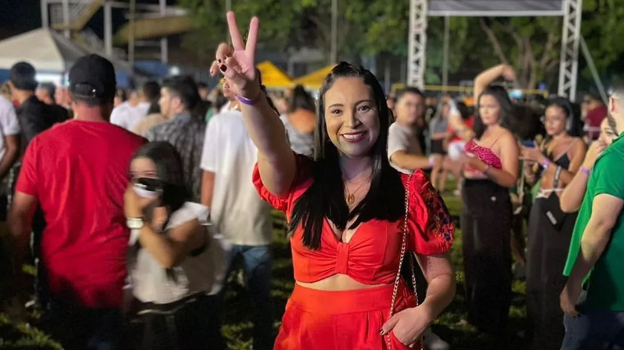 Shauanda Fontes de roupa vermelha, sorrindo e fazendo sinal de paz e amor em show