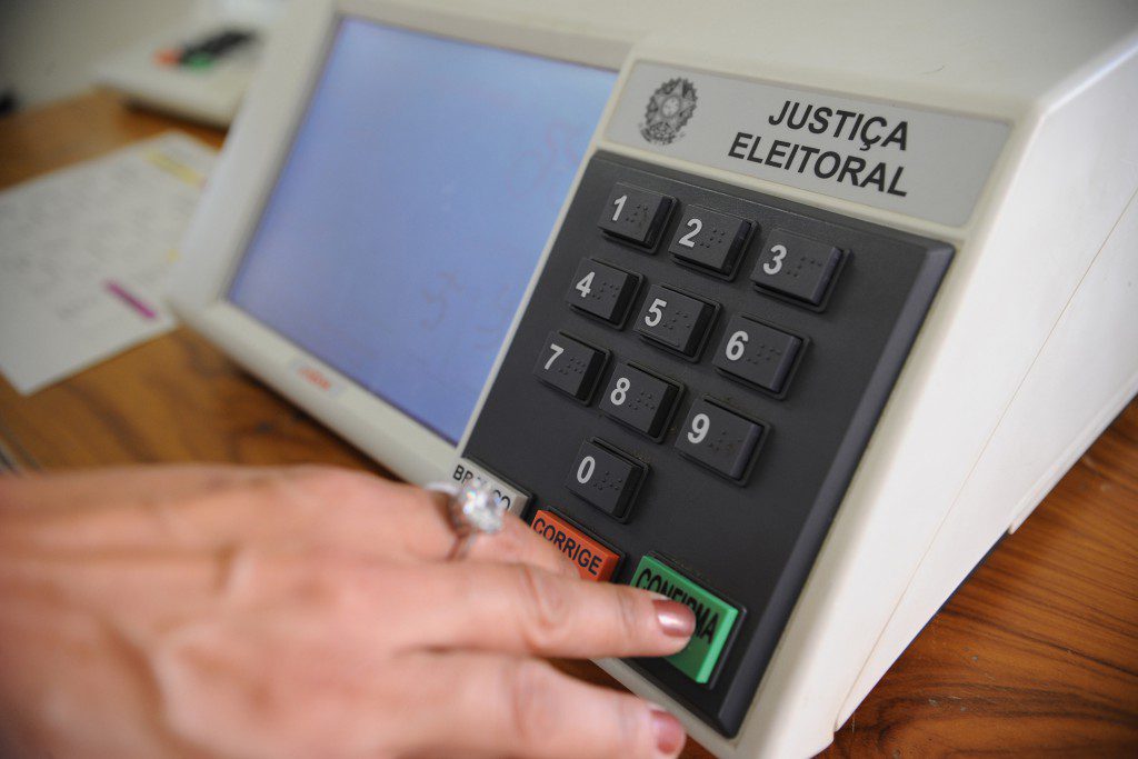 Mão mexendo em urna eletrônica