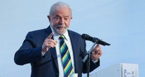Luiz Inácio Lula da Silva falando em microfone e gesticulando, de terno e gravata