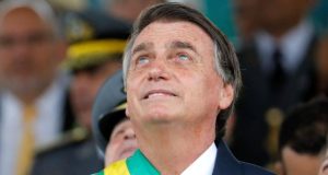Jair Bolsonaro com faixa de presidente, olhando para cima