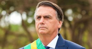 Jair Bolsonaro com faixa de presidente, olhando para a frente com expressão séria