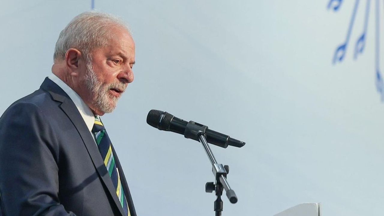 Lula de terno e gravata, de lado, falando em microfone