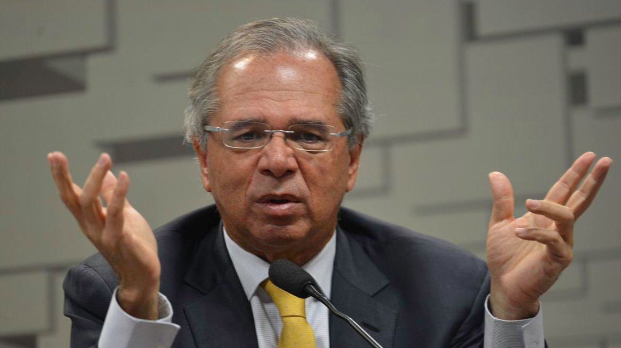 Paulo Guedes falando e gesticulando, com expressão de confusão
