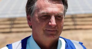 Jair Bolsonaro esboçando sorriso, vestindo camisa branca