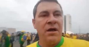 Adriano Camargo Testoni de camisa verde e amarela, falando para a câmera