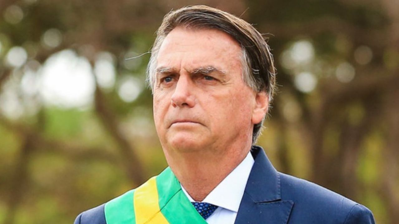 Jair Bolsonaro olhando para frente com expressão séria e faixa presidencial