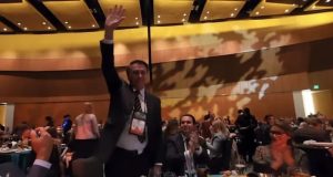 Jair Bolsonaro com o braço erguido e sorrindo em evento
