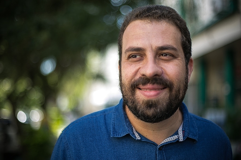 Boulos de camisa polo azul, olhando para o lado e sorrindo