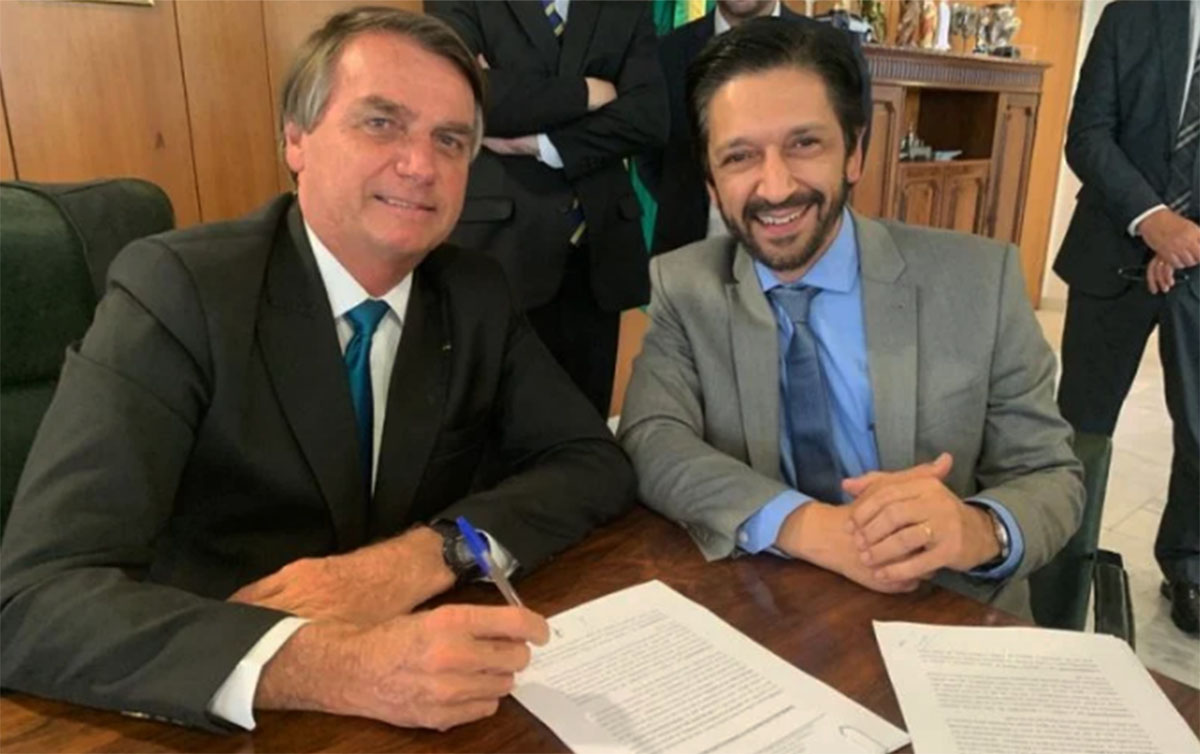 Bolsonaro e Ricardo Nunes sorrindo e sentados lado a lado