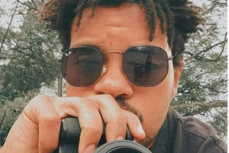 Felipe Ary de Souza posando para foto com câmera e óculos escuros