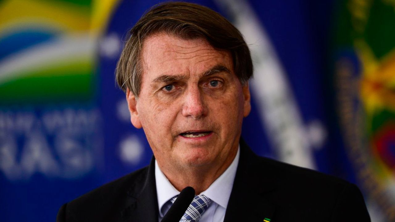 Jair Bolsonaro falando em microfone com expressão confusa