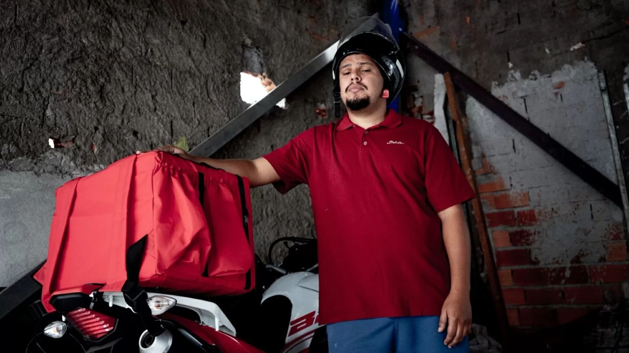 Paulo Galo com roupa vermelha, perto de moto