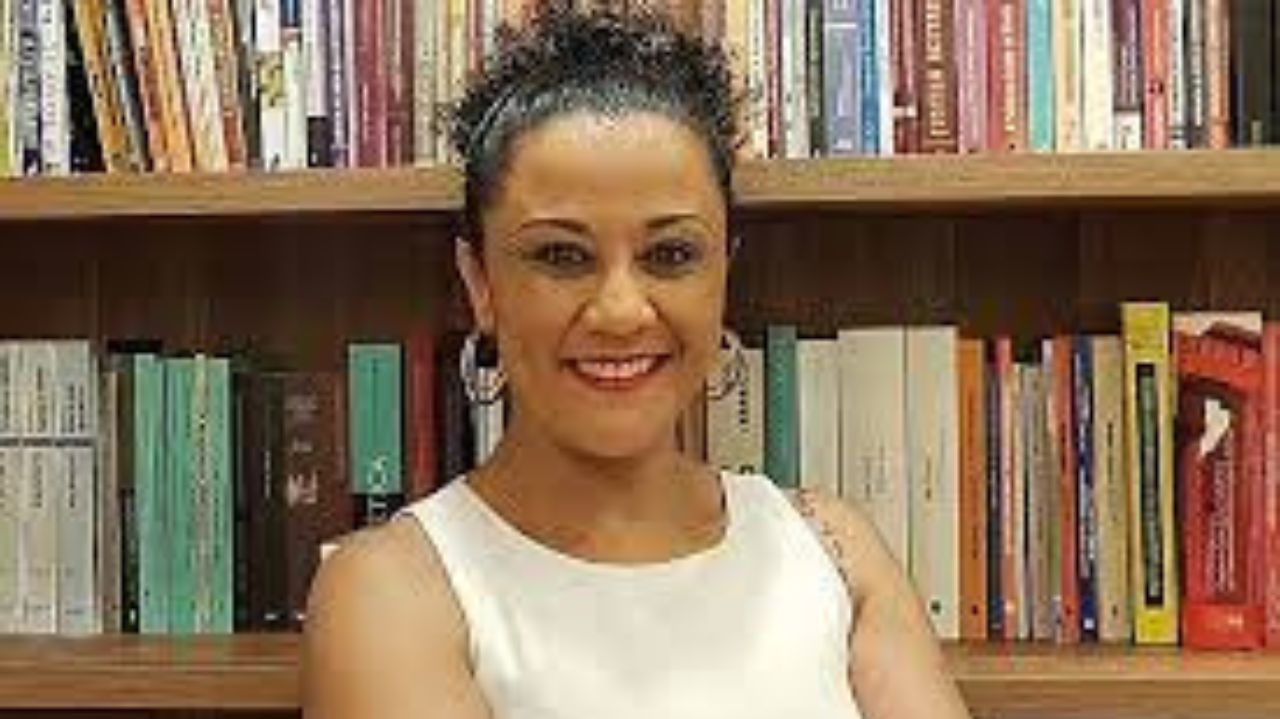 Professora Soraia Mendes sorrindo de cabelo preso e blusa branca