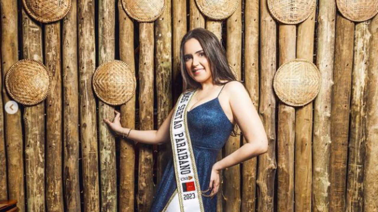 Mayara Ingrid Silva Nitão com vestido azul e faixa de miss, posando e sorrindo