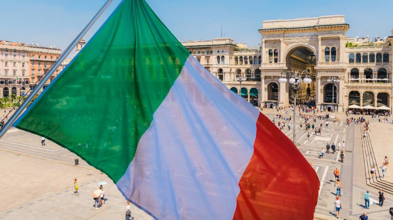 Bandeira da Italia em primeiro plano e ponto turístico atrás