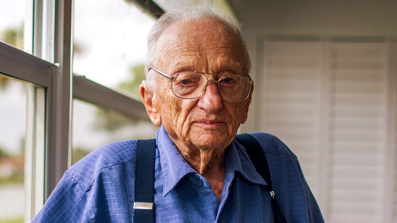 Benjamin Ferencz de roupa azul e óculos, sem sorrir