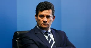 Sergio Moro com expressão de chateação e braços cruzados