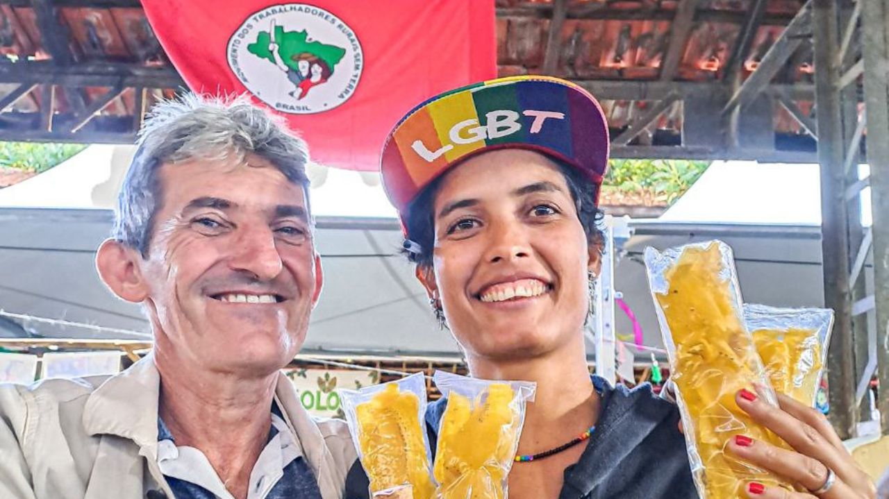 Pessoas segurando comidas com bandeira do MST atrás