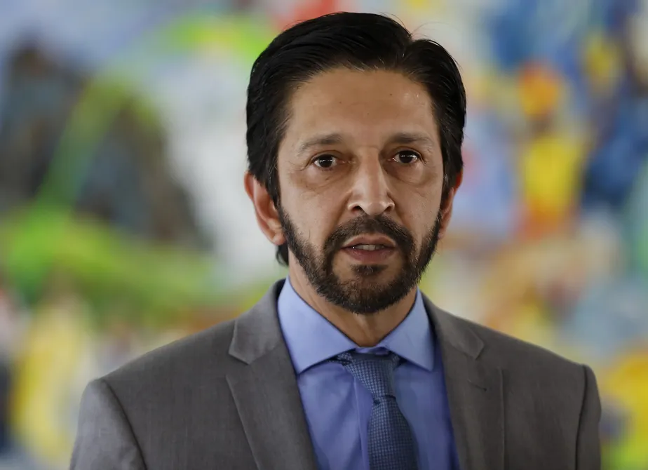 Ricardo Nunes de roupa cinza e azul, com expressão assustada, olhando pra frente