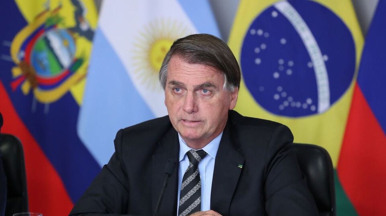 Jair Bolsonaro com expressão séria perto de bandeiras de países