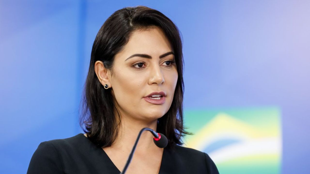 Michelle Bolsonaro de roupa preta e cabelo solto, falando em microfone