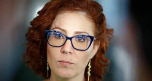 Carla Zambelli com expressão séria e óculos azul
