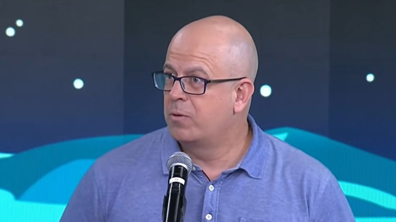Emílio Kerber Filho olhando para o lado e segurando microfone