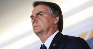 Jair Bolsonaro de perfil, com expressão séria, olhando pra frente