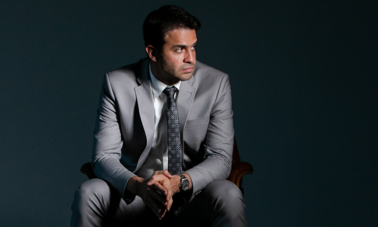 Pablo Marçal de roupa social cinza, sentado e olhando para o lado