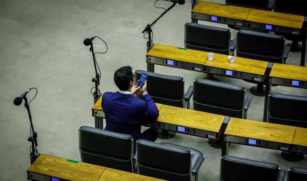 Deltan Dallagnol sozinho, mexendo no celular em planário