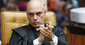 Alexandre de Moraes batendo palmas, com expressão séria