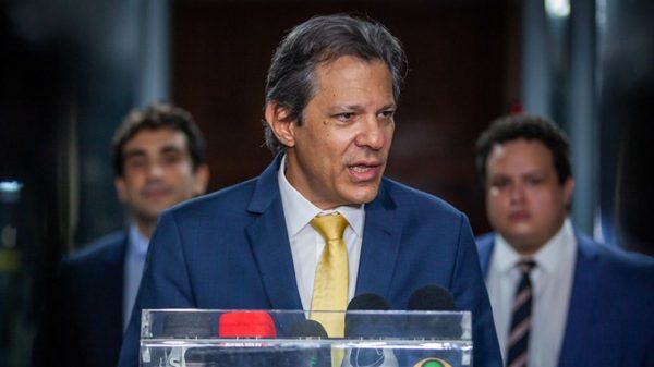 Fernando Haddad de terno e gravata falando para a imprensa