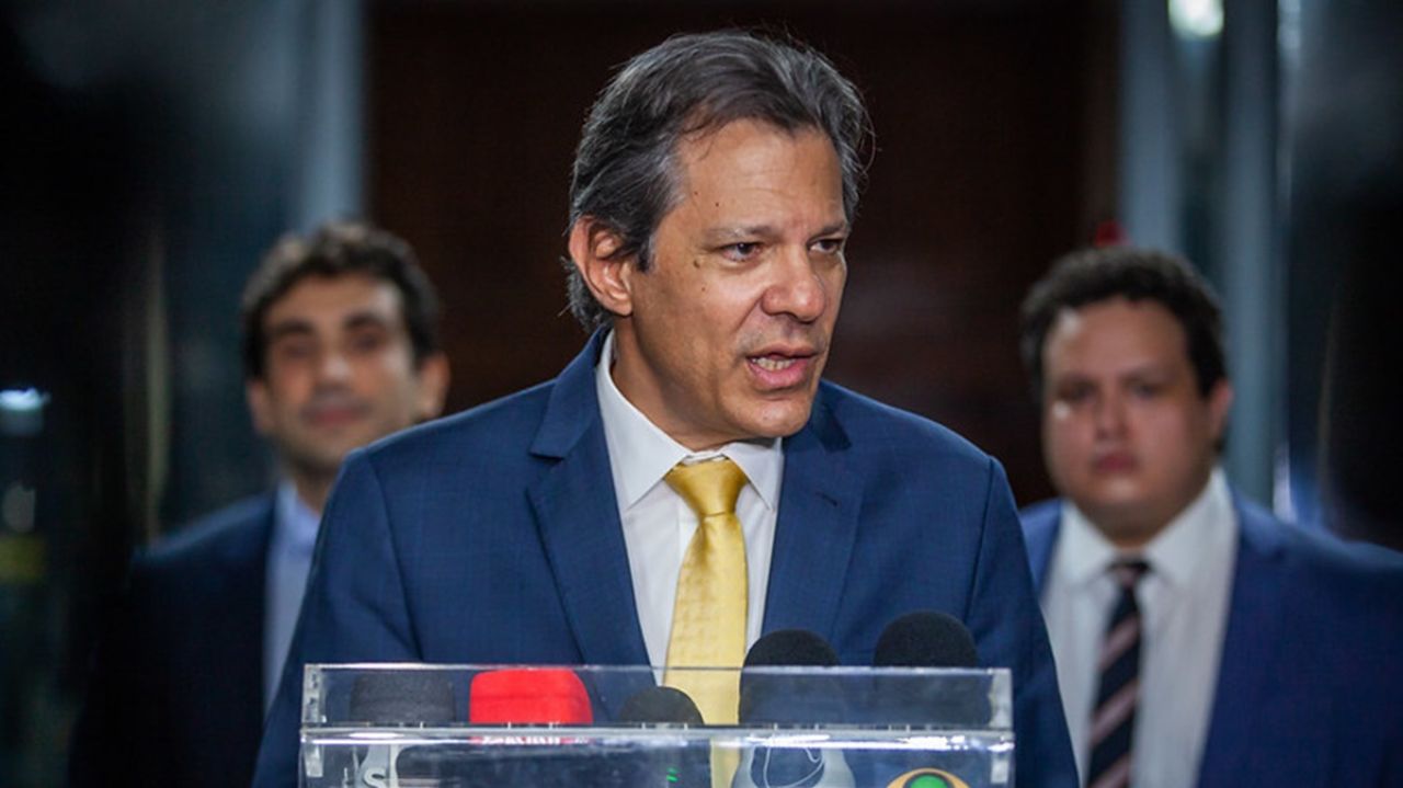 Fernando Haddad de terno e gravata falando para a imprensa