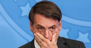 Jair Bolsonaro com uma das mãos no rosto e expressão de preocupação