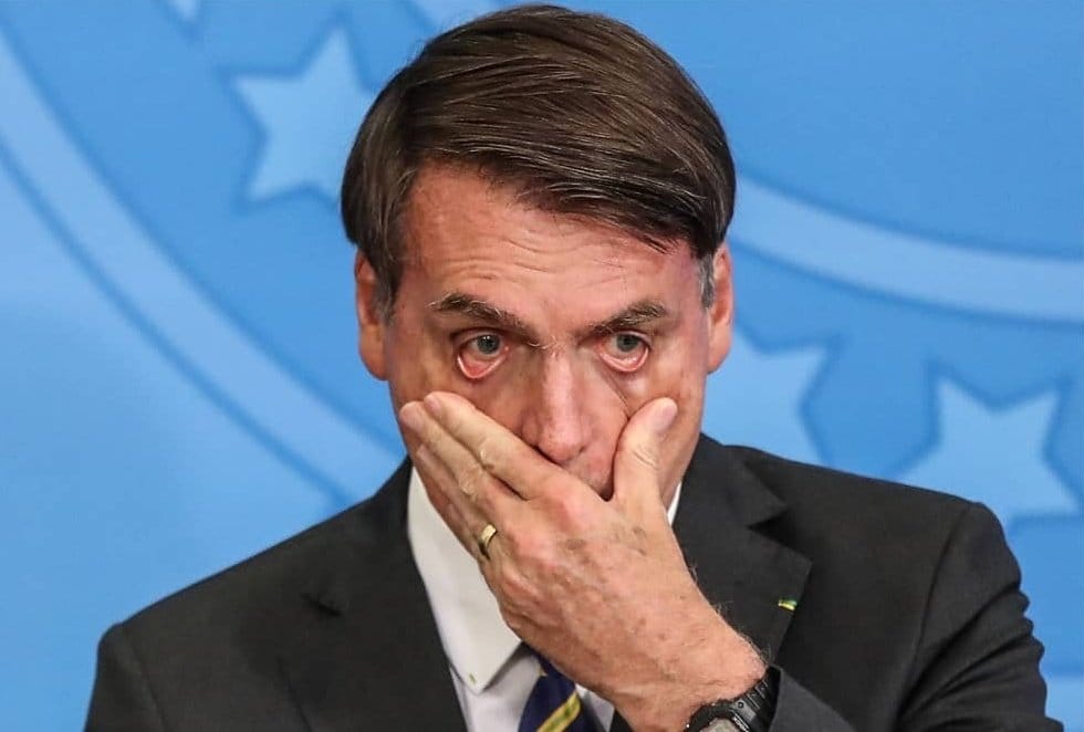 Jair Bolsonaro com uma das mãos no rosto e expressão de preocupação