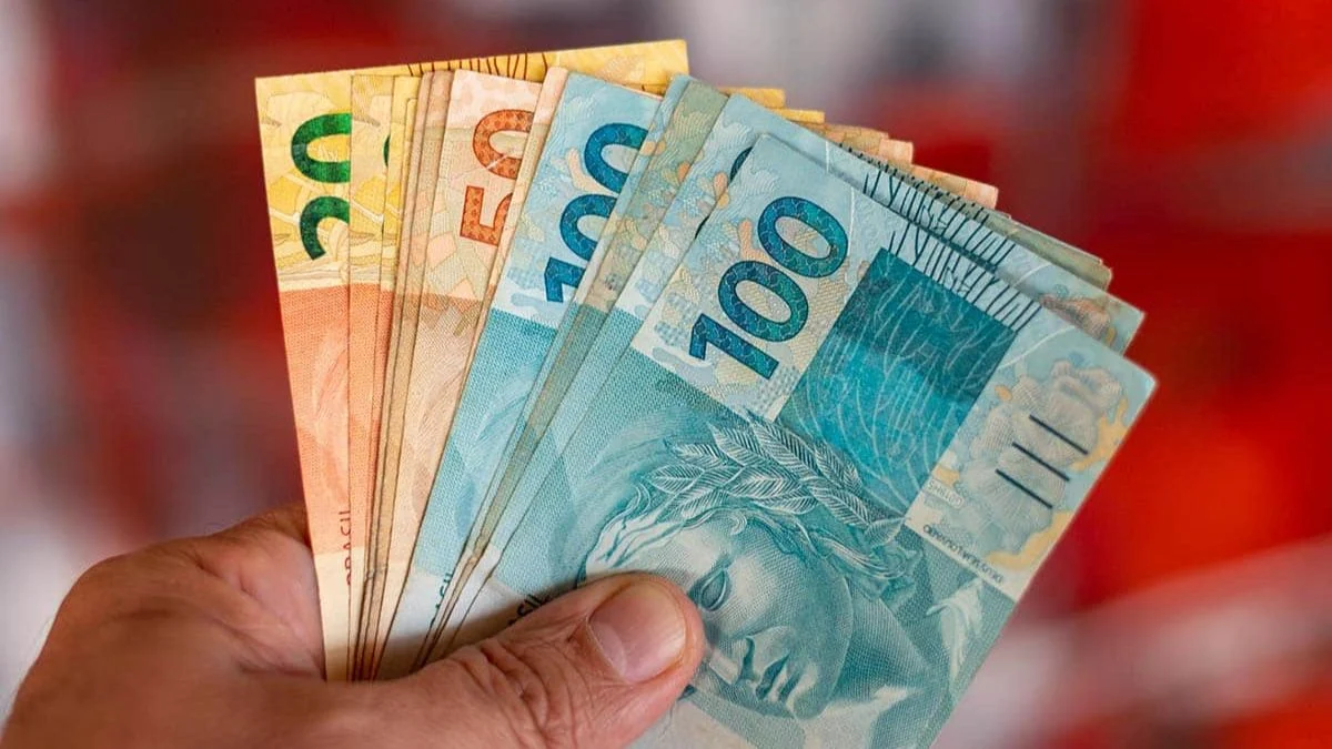 Mão segurando cédulas de reais
