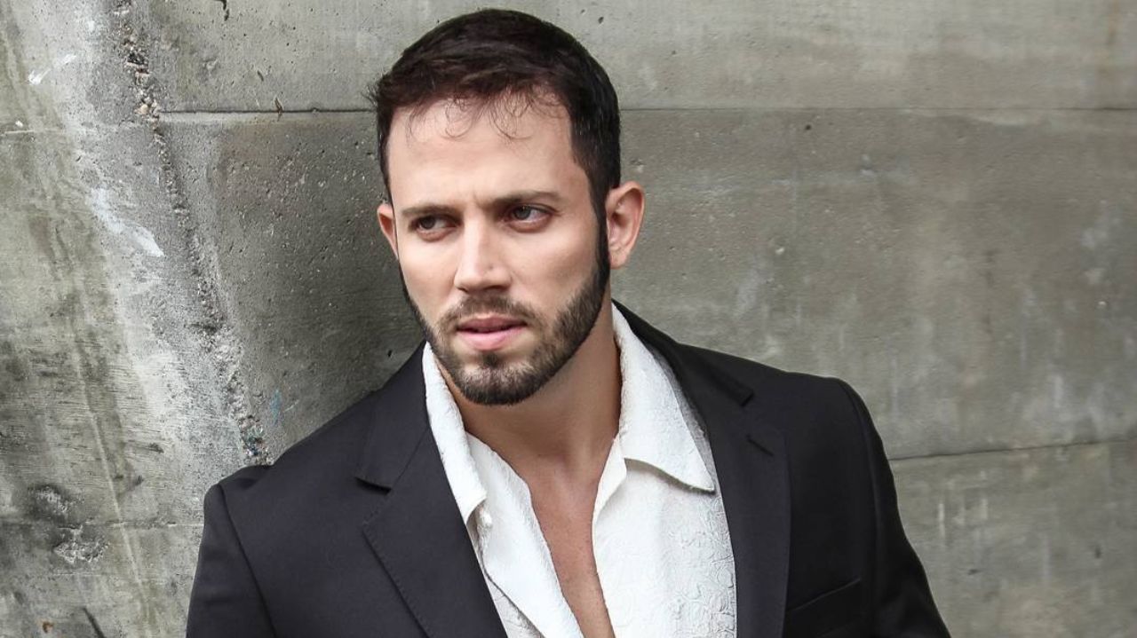 João Almeida de camisa social branca, paletó preto, com expressão séria