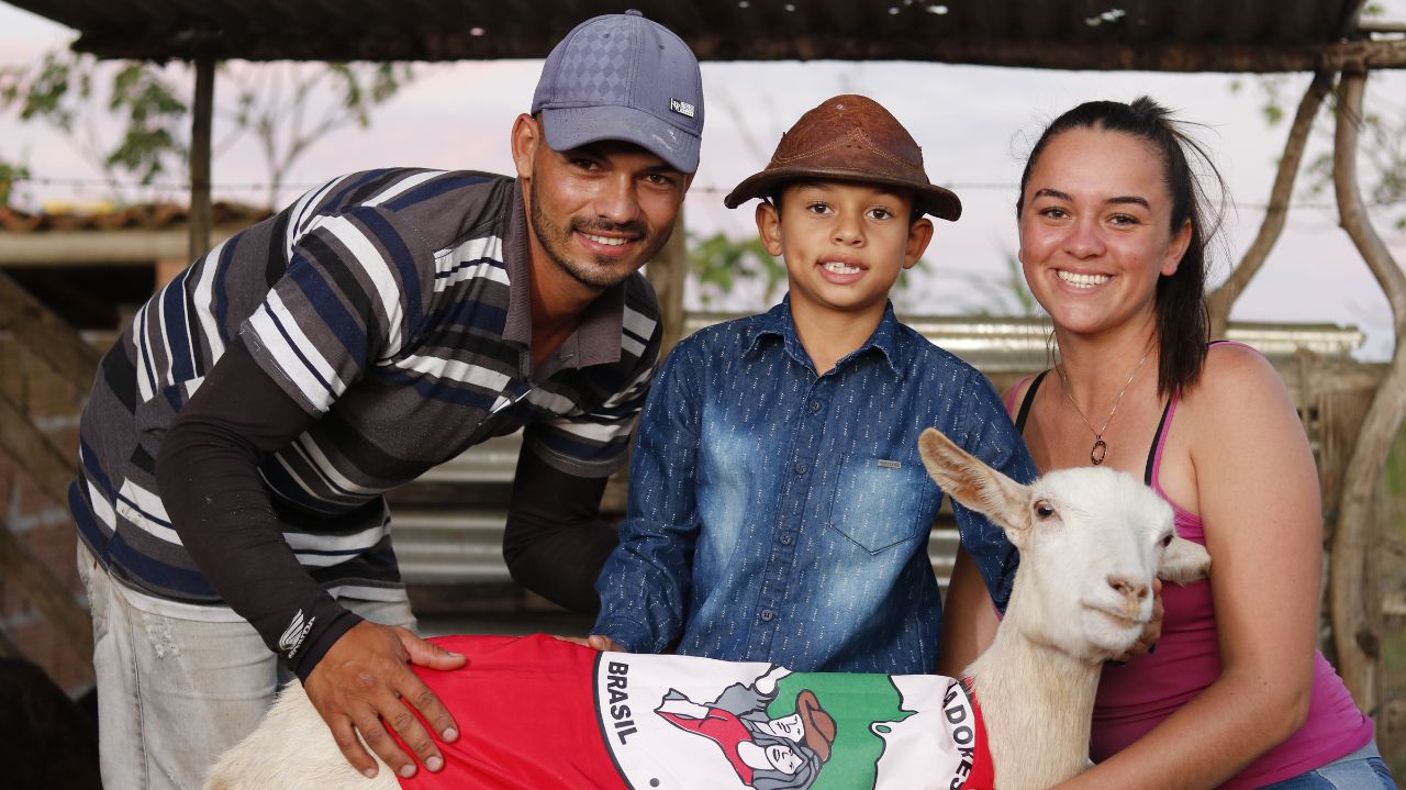 Família posando com animal e bandeira do MST