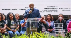 Lula discursando com microfone na mão e roupa social azul