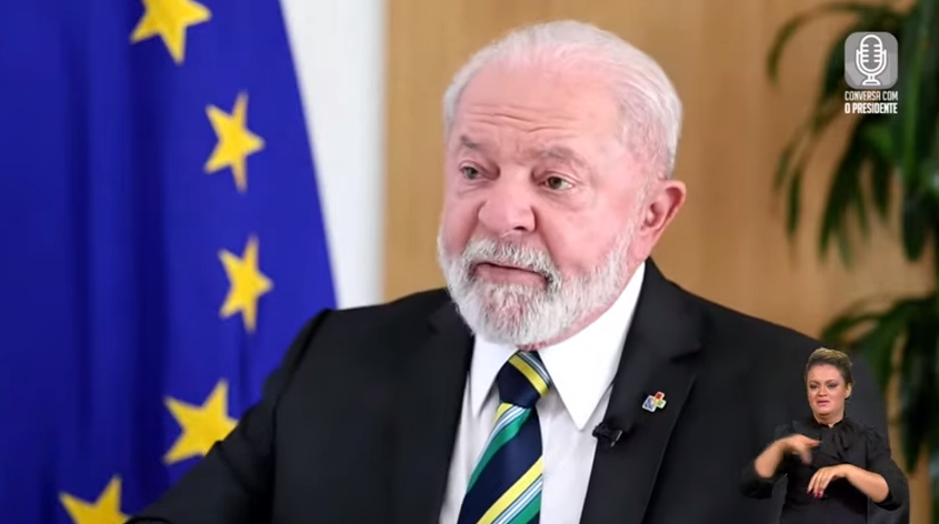 Lula com expressão séria e roupa preta, falando e olhando para o lado