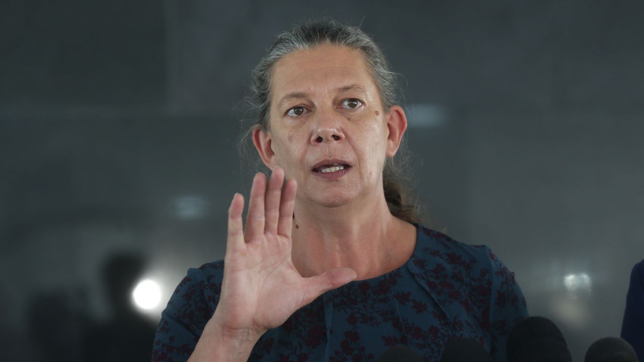 Ana Moser de roupa azul escura, de cabelo preso, apontando a mão para frente