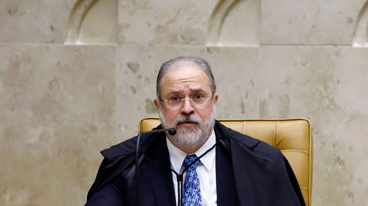 Augusto Aras falando, com expressão de surpresa e óculos