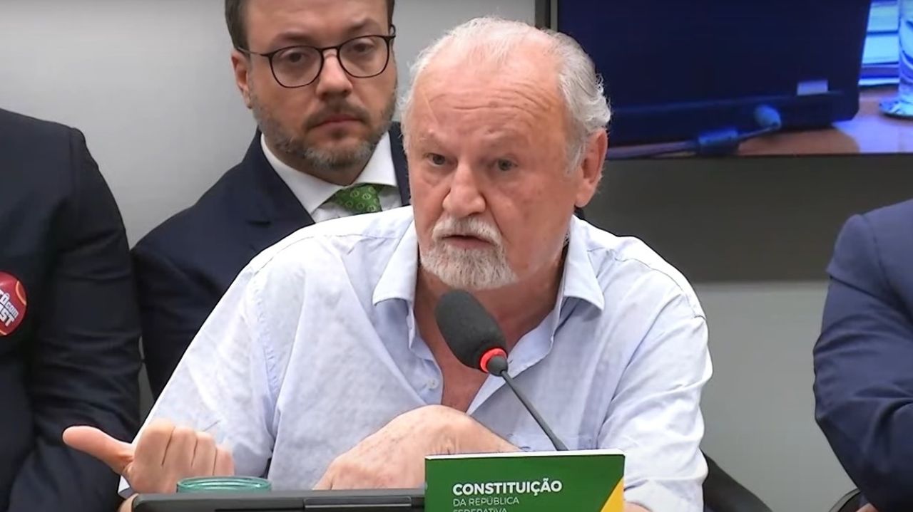 João Pedro Stedile rodeado de pessoas, de roupa branca, falando e gesticulando