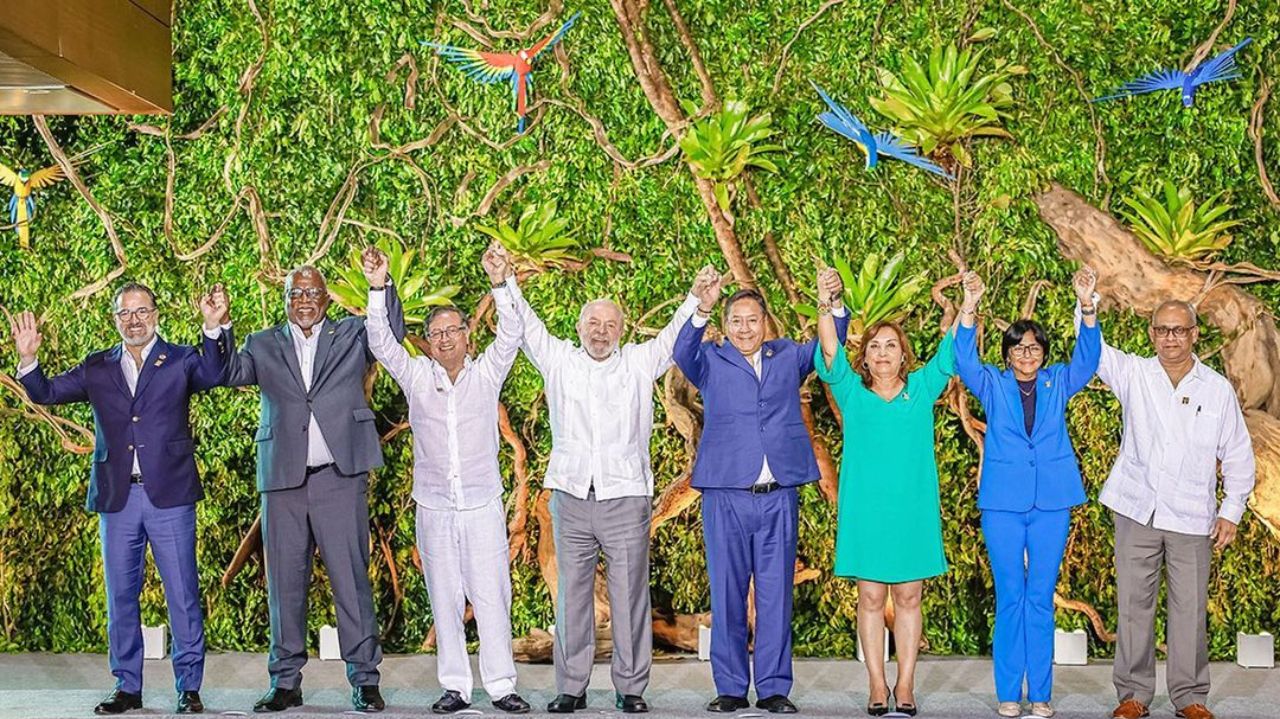 Lula sorrindo de mãos dadas a outros presidentes