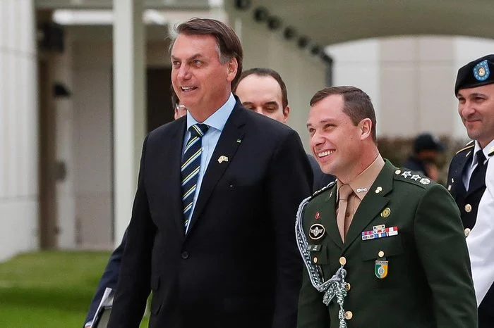 Mauro Cid e Jair Bolsonaro caminhando lado a lado e sorrindo