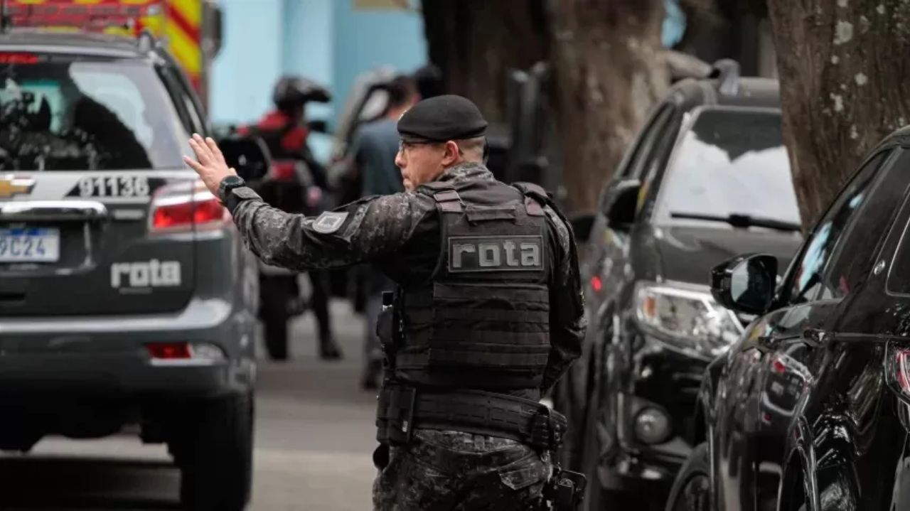Policial da Rota de costas olhando para o lado com braço estendido